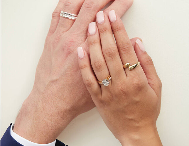 Couple’s hands wearing coordinating engagement and wedding rings in yellow and white gold